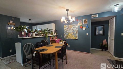 A dining room with a table set for six and a kitchen area with a refrigerator.