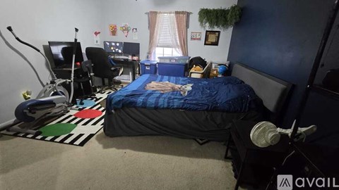 A bedroom with a bed, desk, and exercise equipment.