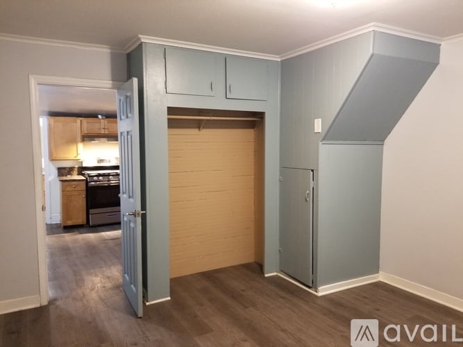 A room with a grey wall and a wooden floor with a white door open.