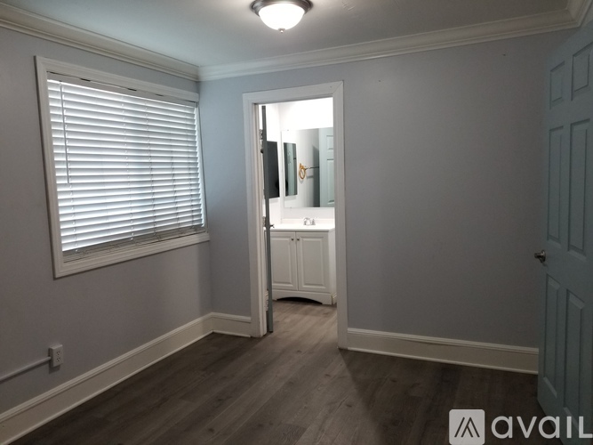 A room with a white door and a window with blinds.