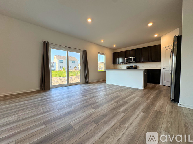 A spacious kitchen with a refrigerator, microwave, and oven, with a view of a house through the sliding glass doors.