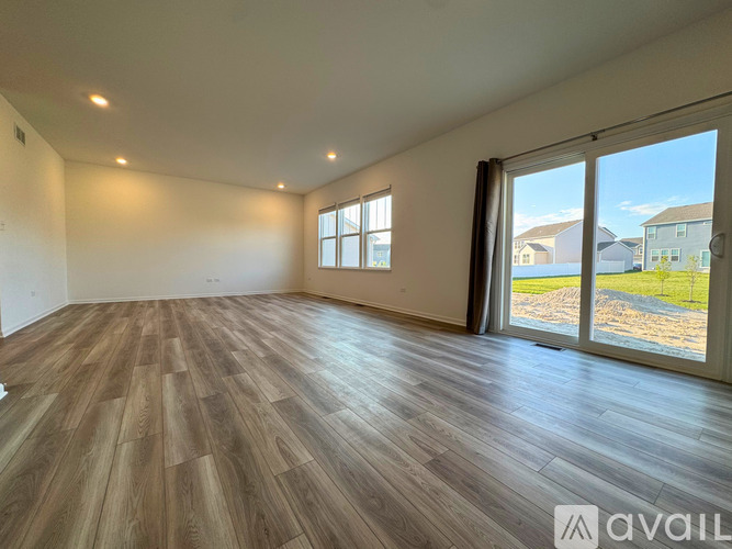 A spacious room with wooden flooring and large windows.