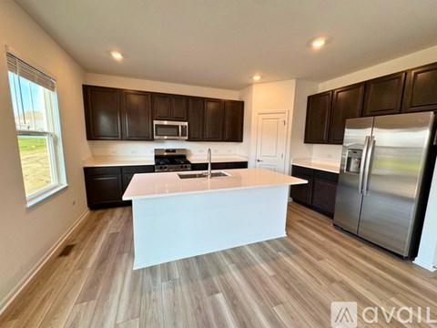 A modern kitchen with dark brown cabinets and stainless steel appliances.