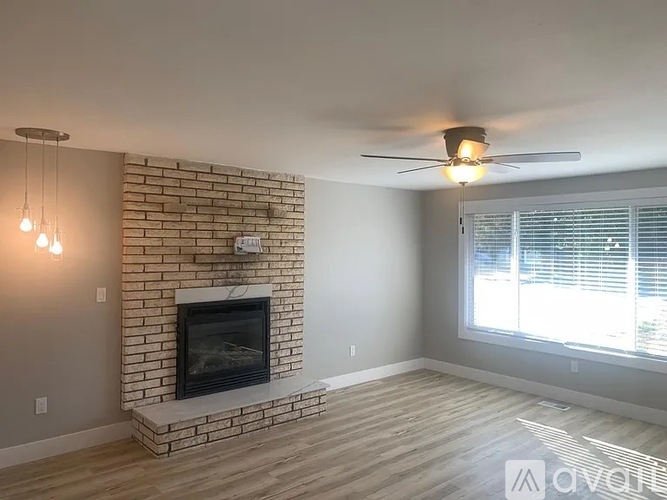 A room with a brick fireplace and a ceiling fan.