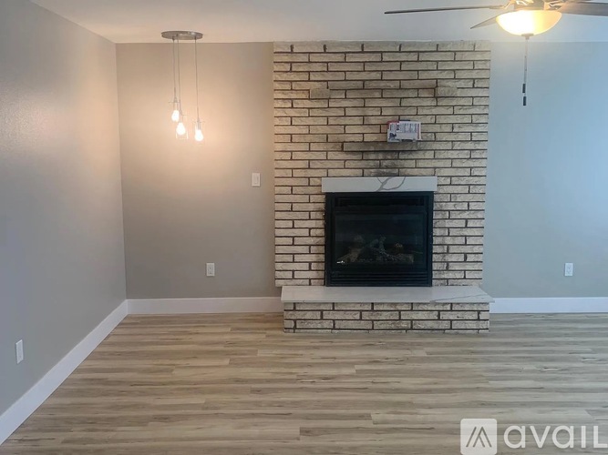 A living room with a brick fireplace and wooden floors.