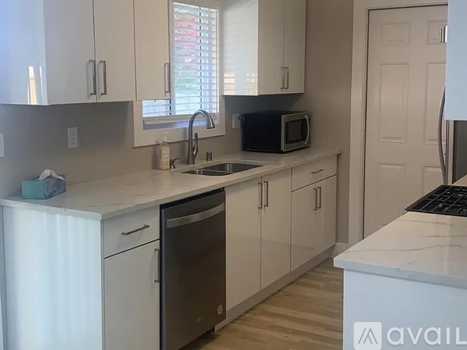A kitchen with white cabinets and a black dishwasher.