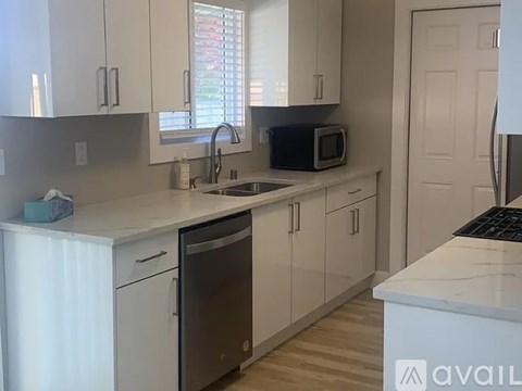 A kitchen with white cabinets and a black dishwasher.