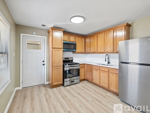A kitchen with wooden cabinets and a stainless steel refrigerator.