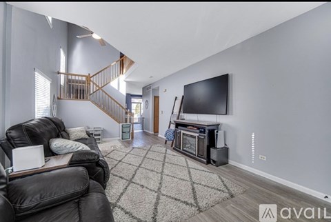 A living room with a black leather couch and a television.
