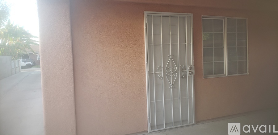 A white gate is on a pink wall.