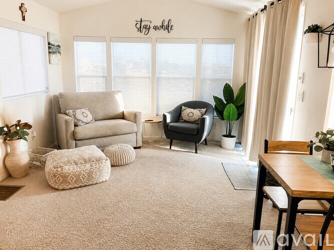 A living room with a couch, chair, ottoman, and a table.
