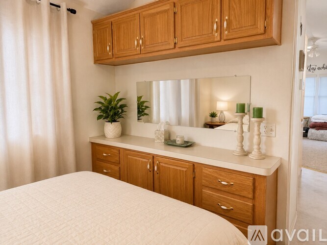 A bedroom with a bed, a vanity with a mirror, and a plant.