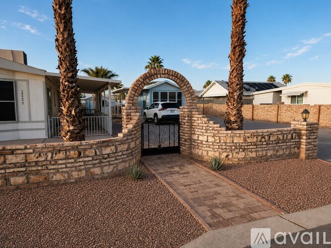 A house with a stone wall and palm trees in front.