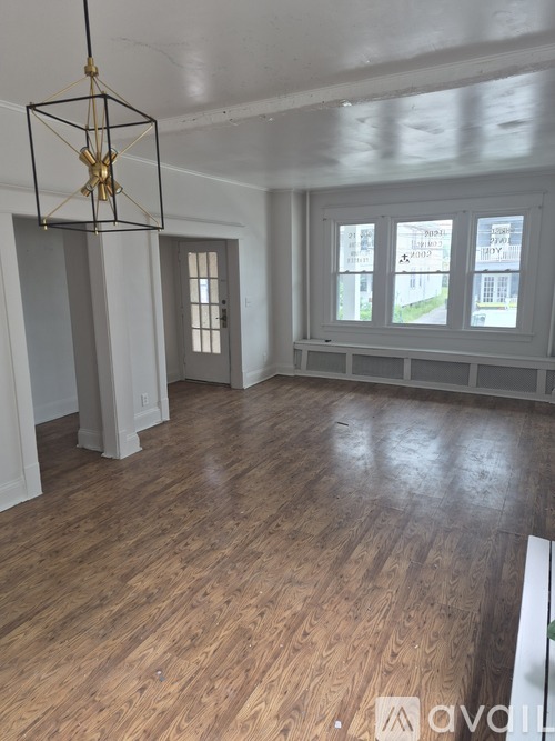 A room with wooden floors and a hanging light fixture.
