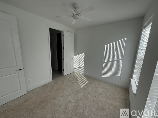 A room with a ceiling fan and a door leading to another room.