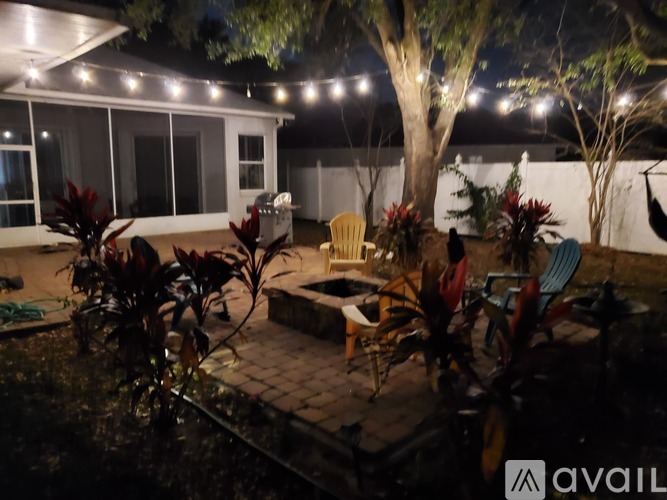 A backyard patio with a table and chairs under string lights.