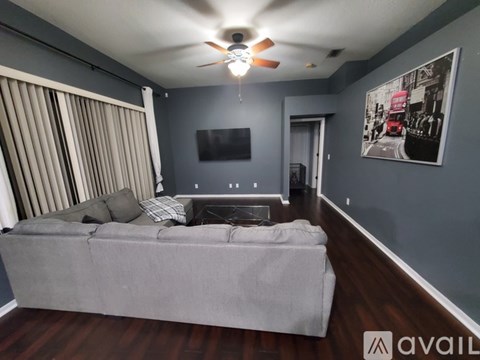 A living room with a grey couch and a ceiling fan.