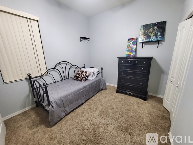 A bedroom with a bed, dresser, and a painting on the wall.