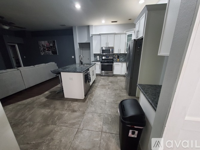 A kitchen with a black trash bin in the middle of the room.