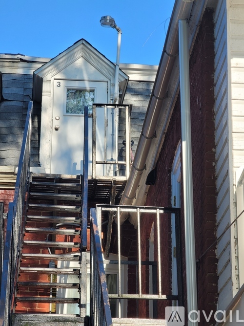 A staircase with a metal railing leads up to a door on a building.