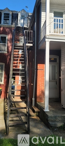 A red brick house with a metal staircase leading to the second floor.