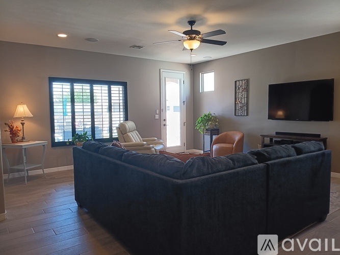A living room with a dark sofa and a ceiling fan.
