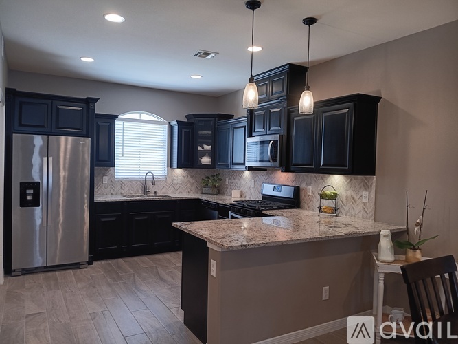 A kitchen with black cabinets and a granite countertop.