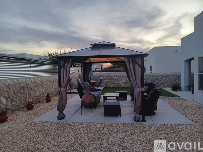 A patio area with a gazebo, chairs, and a table.