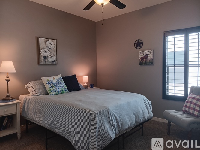 A bedroom with a bed, a chair, and a ceiling fan.