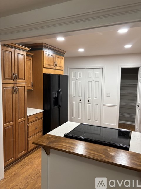 A kitchen with wooden cabinets and a black refrigerator.