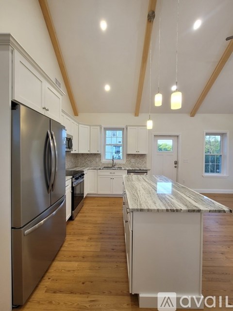 A kitchen with wooden floors and a marble counter top.