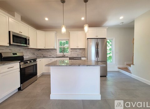 A modern kitchen with white cabinets and a central island.