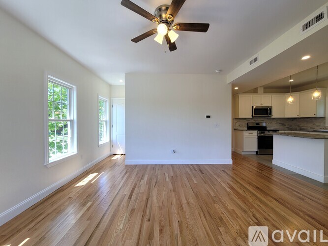 A spacious room with wooden floors and a ceiling fan.