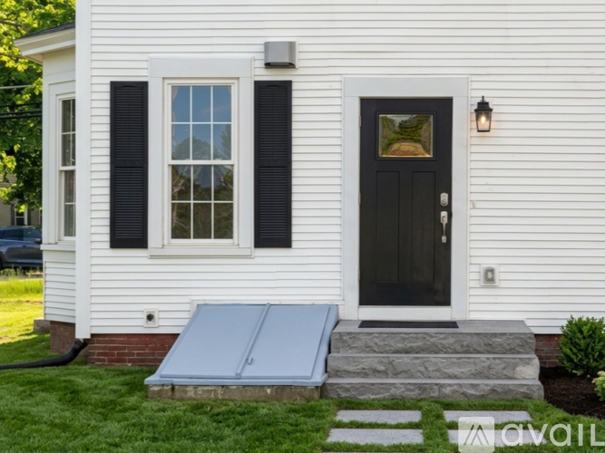 A white house with a black door and a window with black shutters.