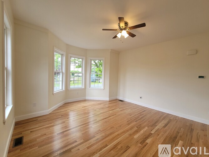 A room with wooden flooring and a ceiling fan.