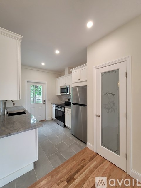 A kitchen with white cabinets and a wooden floor.