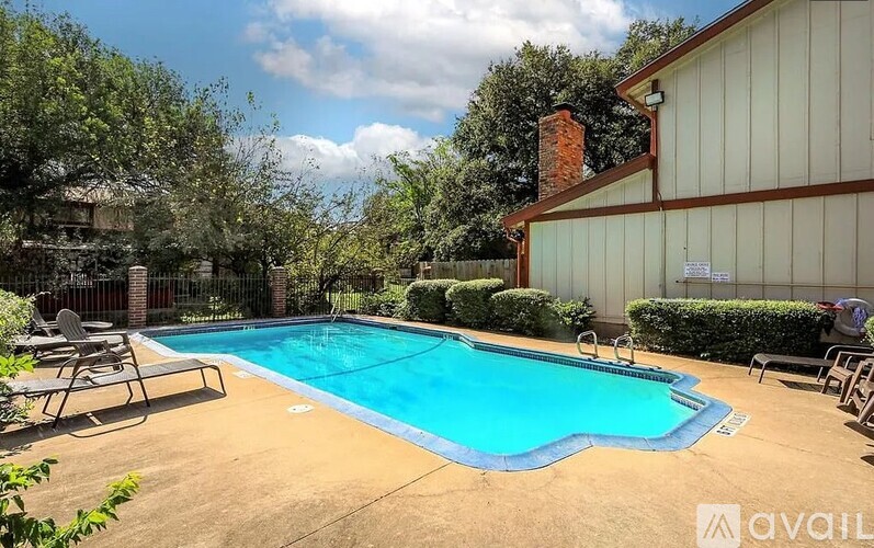 A pool surrounded by a fence and trees.