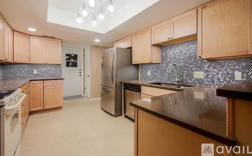 A kitchen with wooden cabinets and a black and white tiled backsplash.