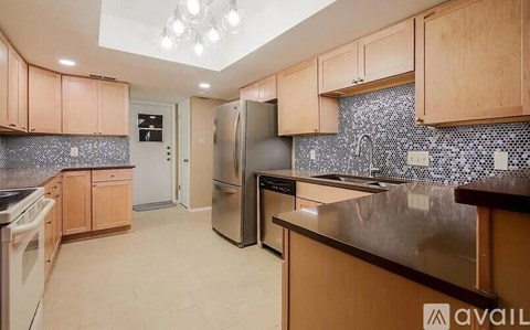 A kitchen with wooden cabinets and a black and white tiled backsplash.