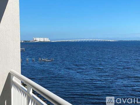 A view of a body of water with a white railing in the foreground and a building in the distance.