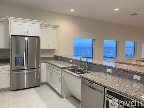 A modern kitchen with a stainless steel refrigerator and granite countertops.