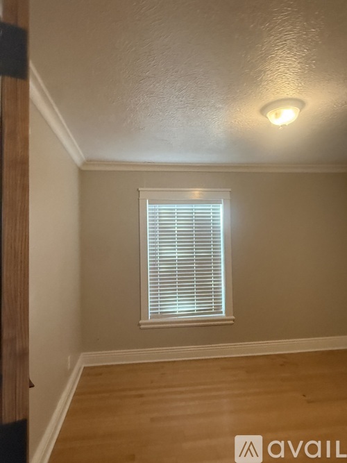 A room with a window covered by white blinds.