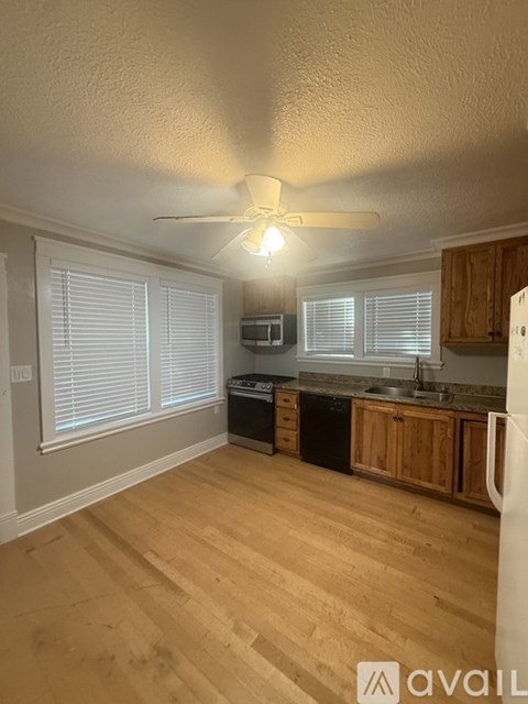 A kitchen with wooden floors and a ceiling fan.