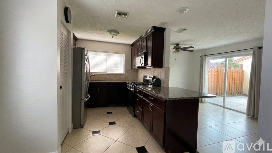A kitchen with a black counter top and brown cabinets.