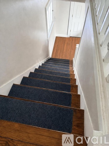 A staircase with a dark carpeted runner and wooden steps.