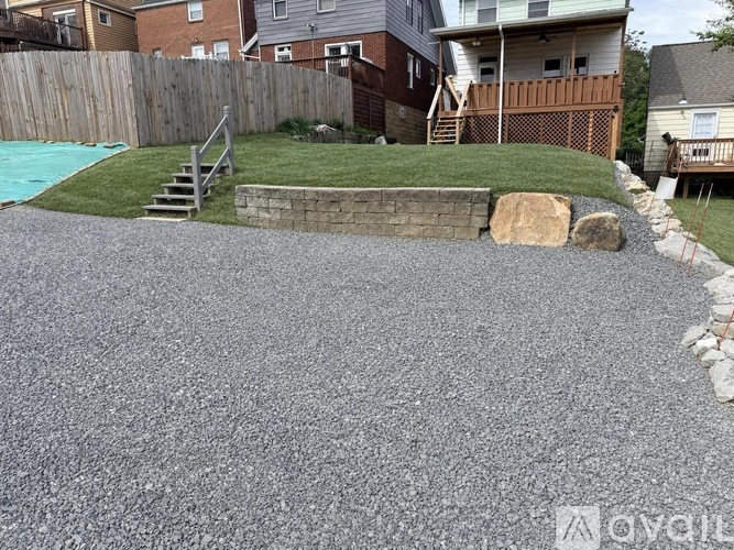 A residential backyard with a gravel patio and a small pool.