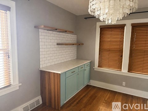A kitchen with a white chandelier, wooden cabinets, and a white subway tile backsplash.
