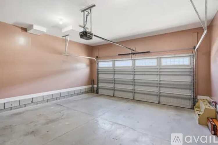 A spacious garage with a closed shuttered door and a fan hanging from the ceiling.