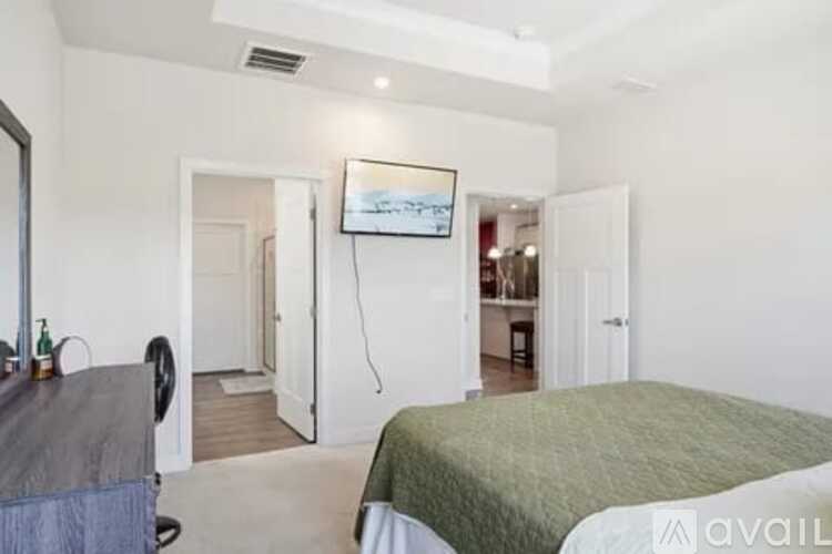 A bedroom with a bed, a chair, and a painting on the wall.