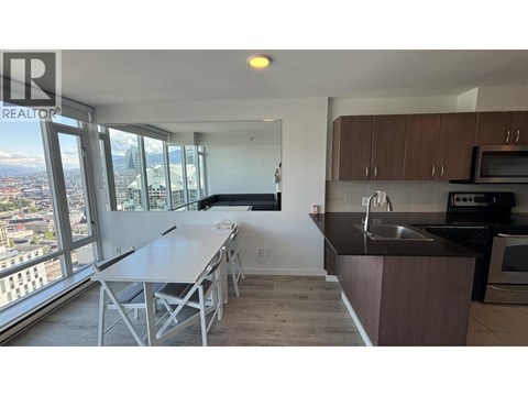 A kitchen with a table and chairs in front of a window with a view of the city.